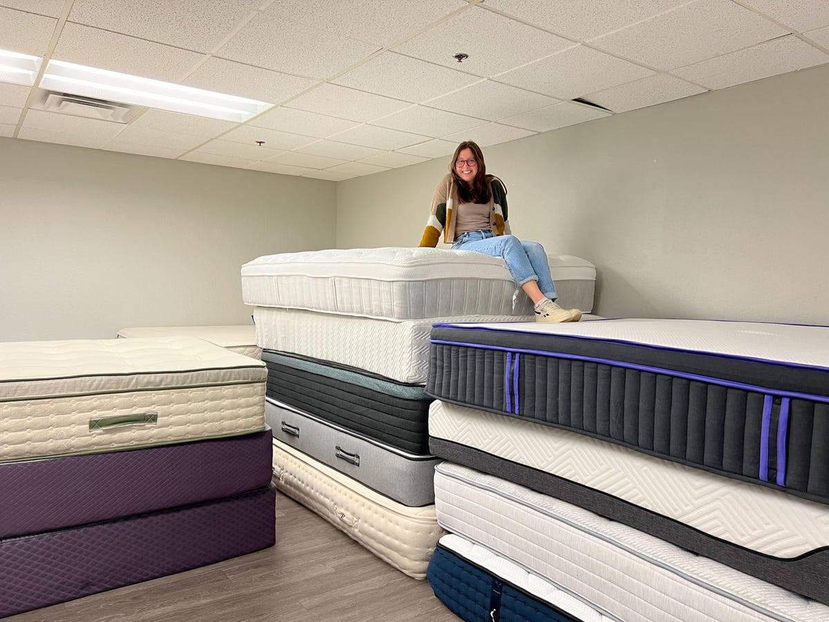 Caroline on top of a stacks of mattresses in the mattress warehouse.