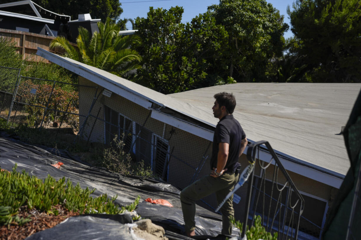 A reporter stands near a home that collapsed due to ongoing landslides in Rancho Palos Verdes, Calif., Tuesday, Sept. 3, 2024. (AP Photo/Jae C.