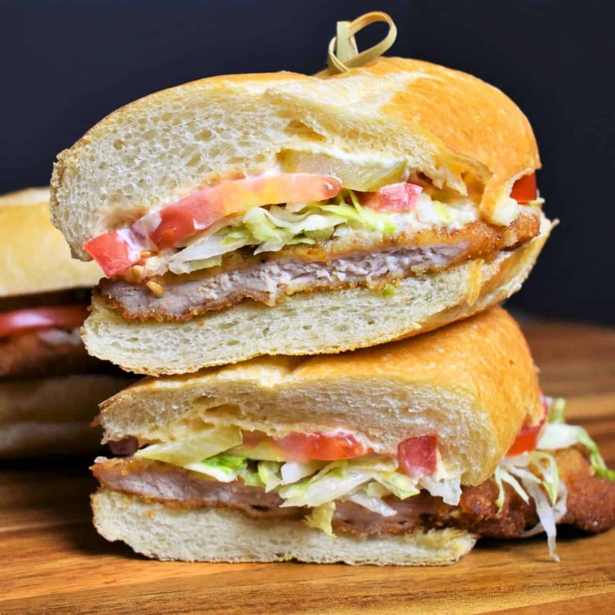 Fried Pork Sandwich, served on a sub roll with shredded lettuce, tomatoes and mayo, cut in half and stacked.