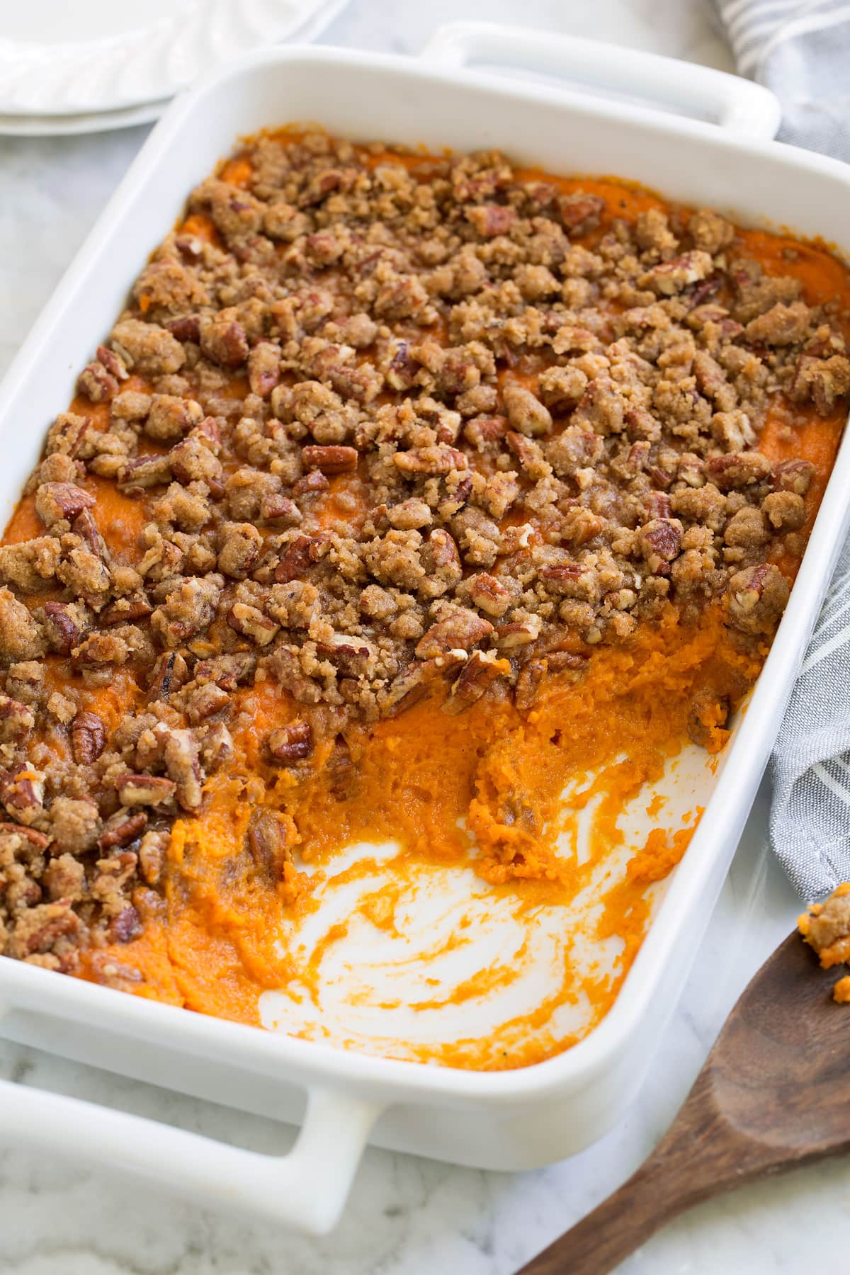 Sweet Potato Casserole with a cinnamon pecan crumble on top, served in a white casserole dish.