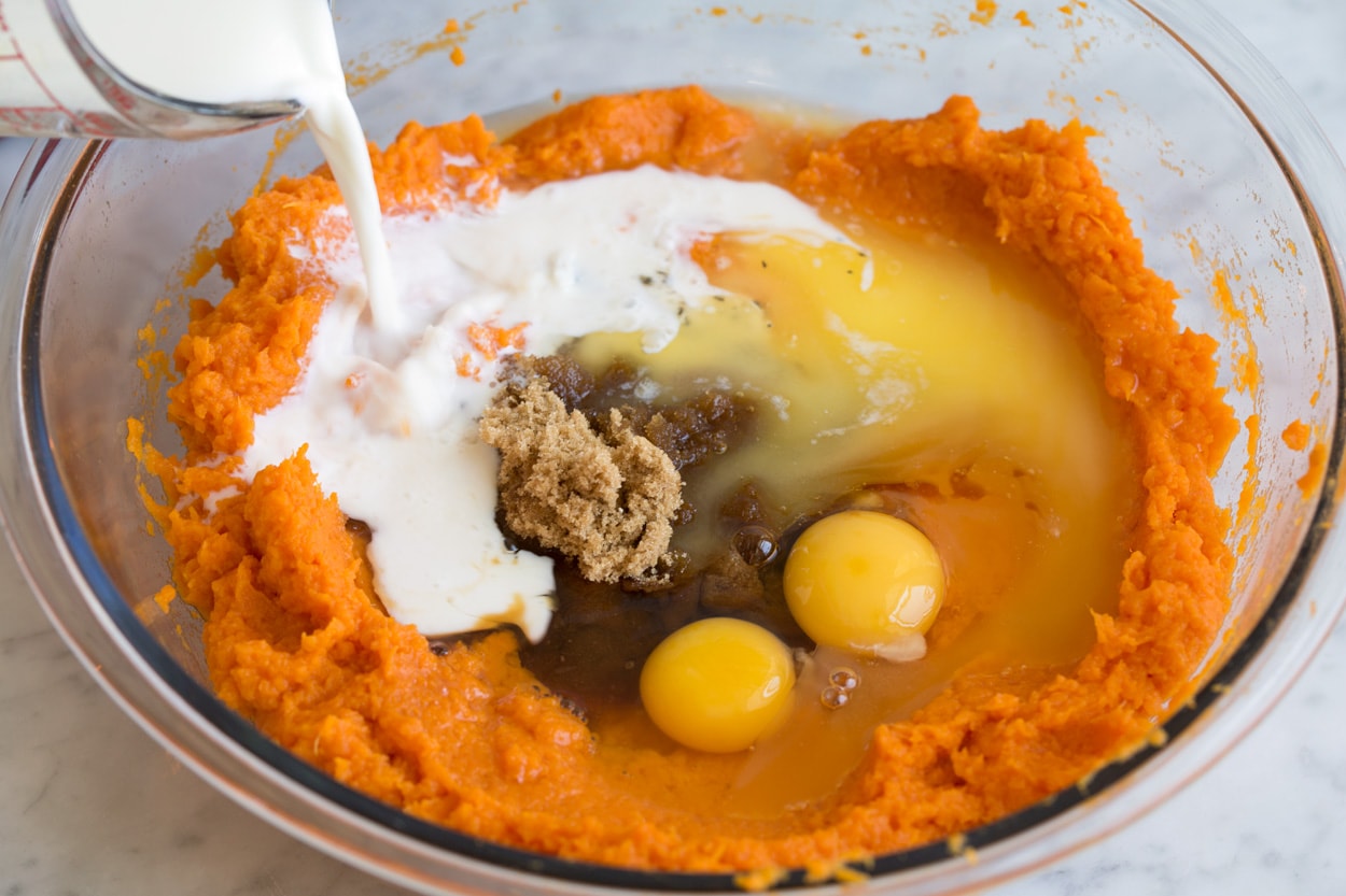 Mashed sweet potatoes, milk, eggs, brown sugar, spices in mixing bowl to make sweet potato casserole.