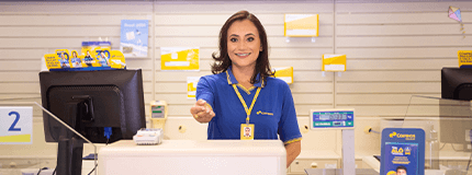 Atendente dos Correios em balcão de agência dos Correios, estendendo a mão em sinal de recepção.