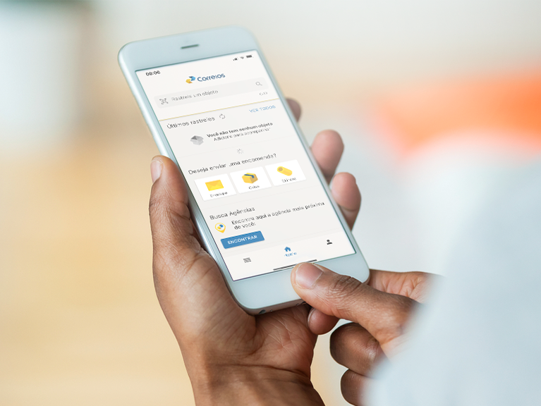 Mãos segurando celular, exibindo tela do aplicativo dos Correios.