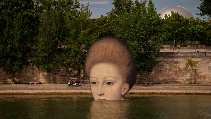 A technician drives in a cart by reproductions of artworks decorating the banks of the River Seine, the day before the opening ceremony of the 2024 Summer Olympics, Thursday, July 25, 2024, in Paris, France. (AP Photo/Vadim Ghirda)