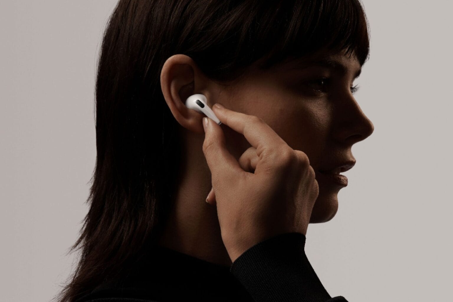 A woman places a refurbished first-gen AirPods Pro earbud in her ear.