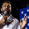 FBI Director-designate Kash Patel speaking into a microphone next to a U.S. flag