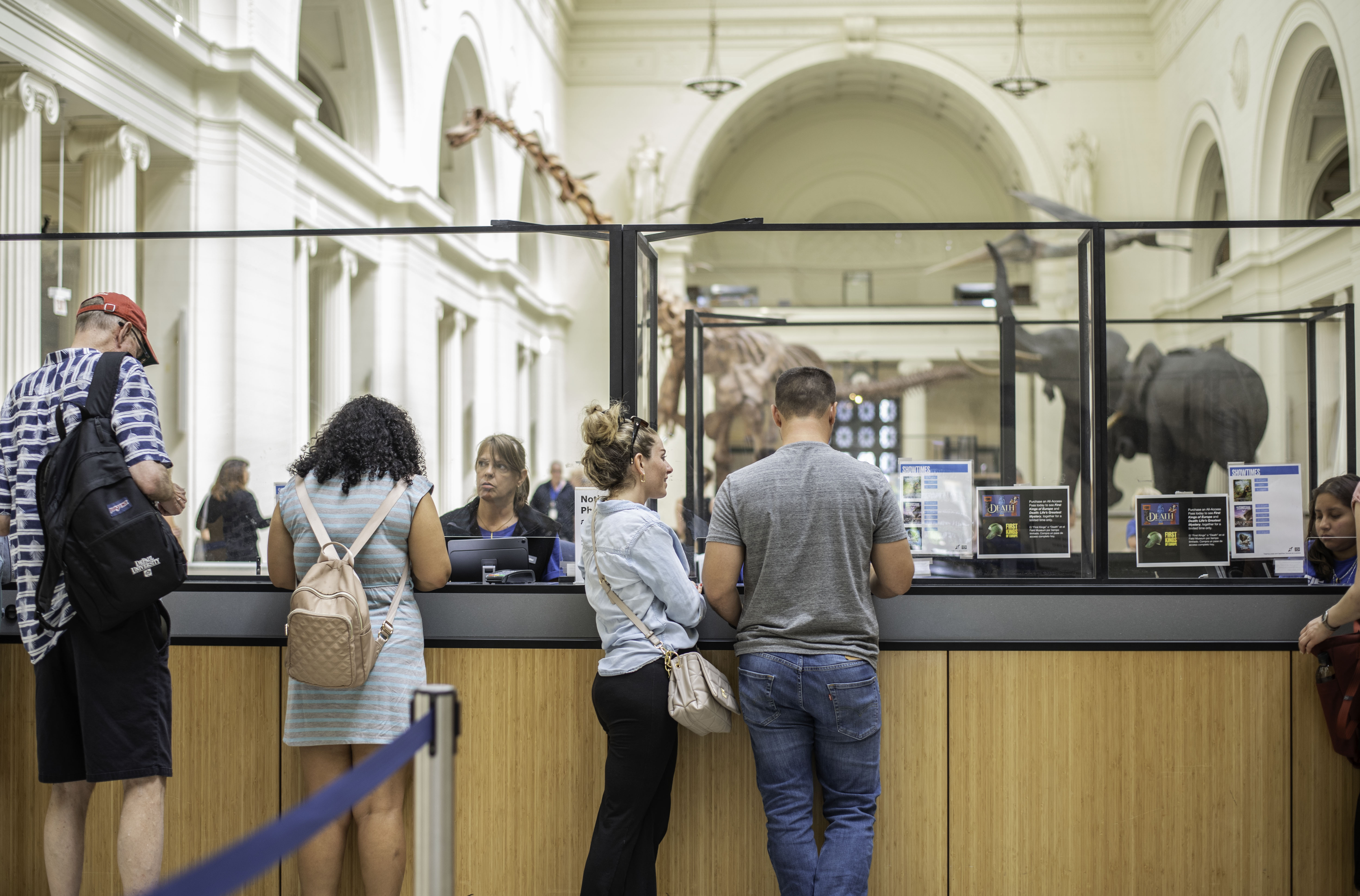 Several people stand at the ticket windows in the museum's main hall