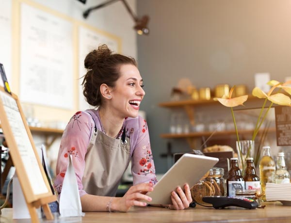 Peninsula Group Limited - A cafe worker smiling and laughing while using a computer tablet