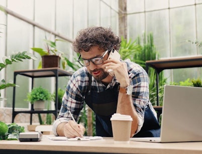 Peninsula Group Limited - An employer in a greenhouse setting talking on the phone to an advisor