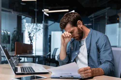 Person working on laptop looking stressed