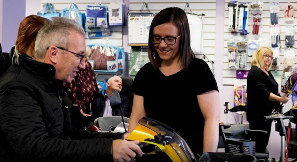 A woman helping a customer on a mobility scooter.