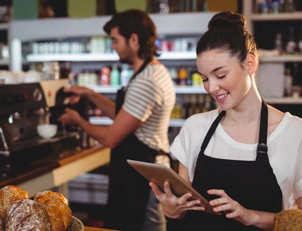 Coffee shop workers behind a till.