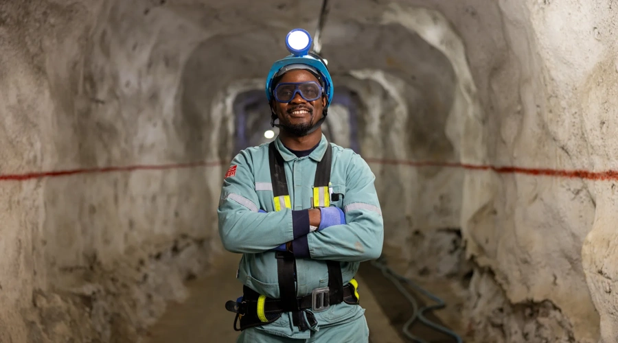 Dell Young Leaders alum Thapelo smiles while wearing his mining gear at work.