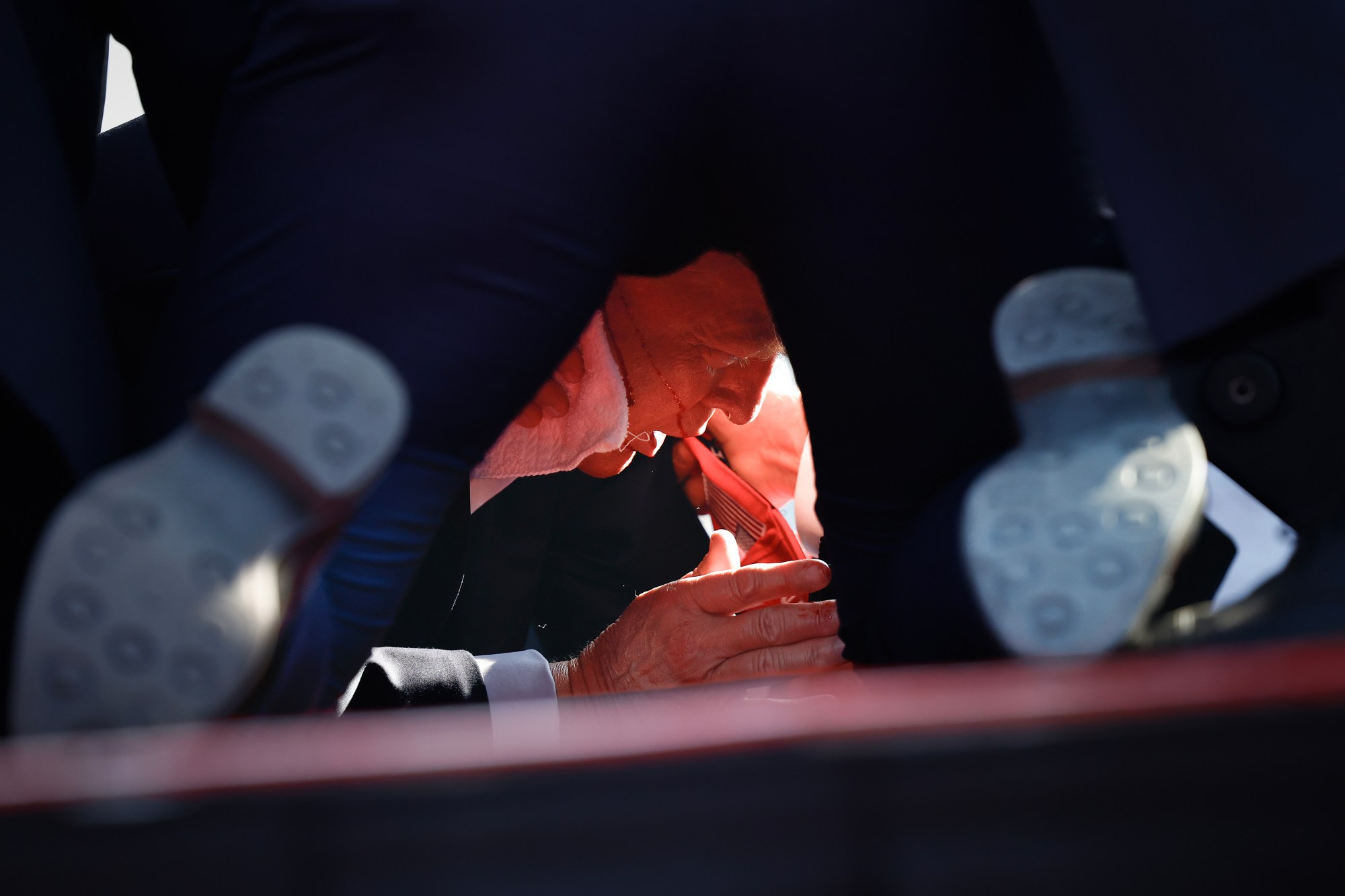 BUTLER, PENNSYLVANIA - JULY 13: Secret Service tend to republican presidential candidate former President Donald Trump onstage after he was grazed by a bullet at a rally on July 13, 2024 in Butler, Pennsylvania. Butler county district attorney Richard Goldinger said the shooter is dead after injuring former President Trump, killing one audience member and injuring another in the shooting. (Photo by Anna Moneymaker/Getty Images)