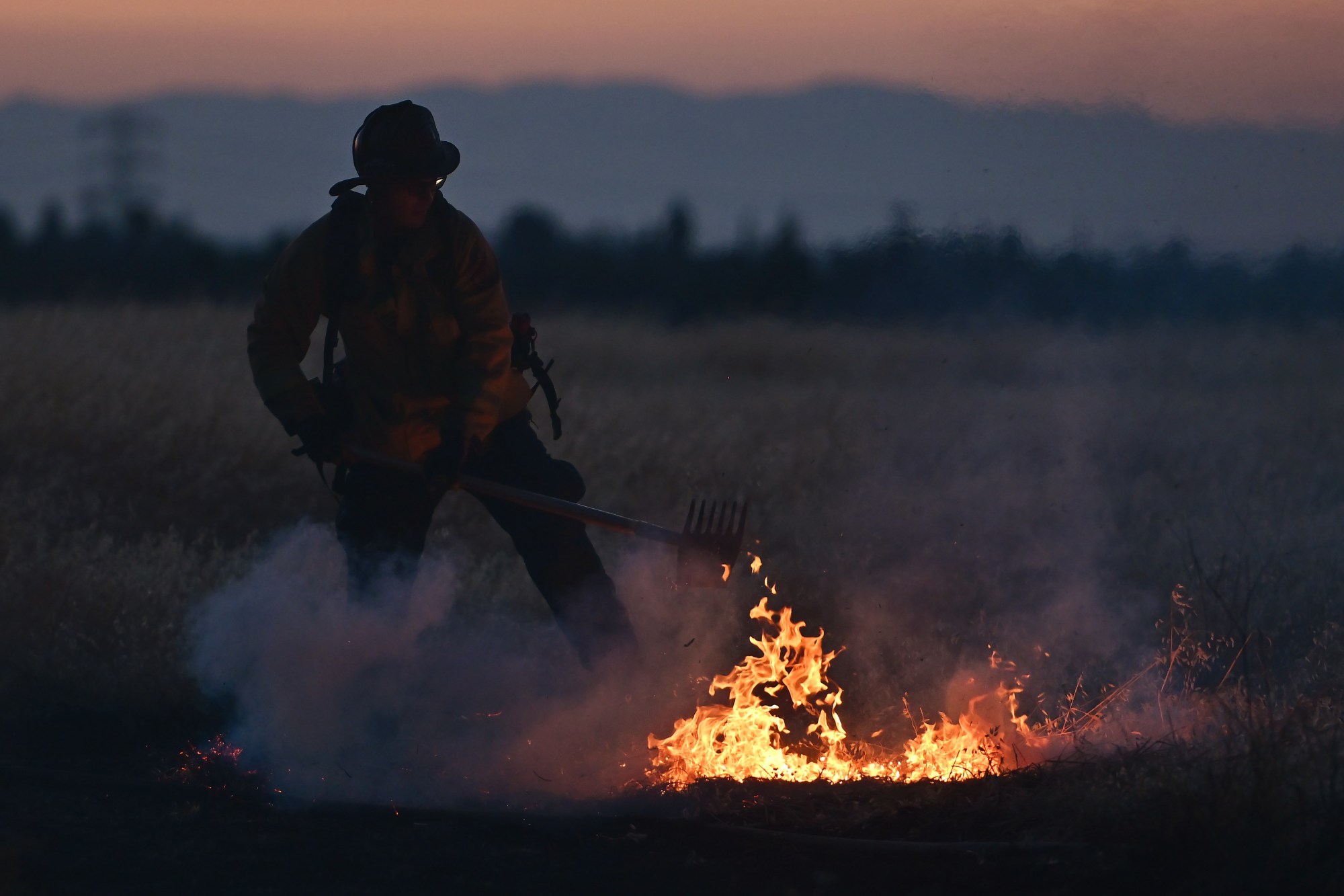 A Contra Costa Firefighter extinguishes a hot spot at a vegetation fire by illegal fireworks on Somersville Road during the Fourth of July celebrations in Antioch, Calif., on Thursday, July 4, 2024. (Jose Carlos Fajardo/Bay Area News Group)