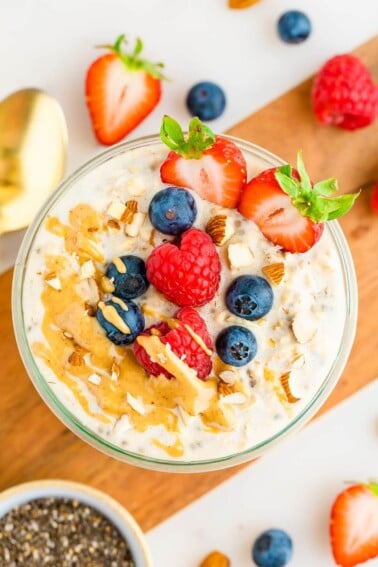 Jar of protein overnight oats topped with berries, almonds and peanut butter.