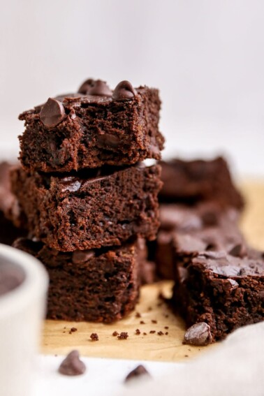 Three brownies stacked on top of one another. The top brownie has a bite taken out of it.