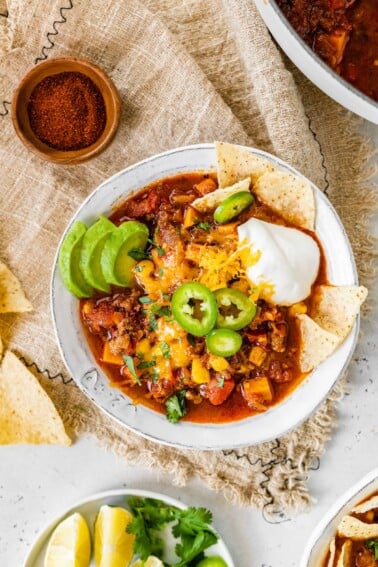 A bowl of no bean chili topped with cheese, jalapeños, avocado, sour cream and chips.