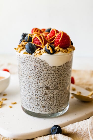 One protein chia pudding jar topped with fresh raspberries, blueberries, blackberries, greek yogurt and a drizzle of nut butter.