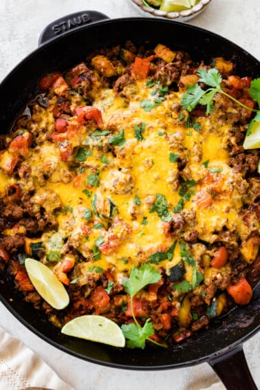 Ground beef and squash in a large skillet topped with melted cheddar cheese.