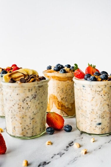 Four glass jars of overnight oats topped with fresh berries.