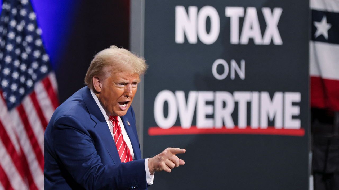 Donald Trump speaks beside a sign saying "No Tax on Overtime" during a campaign event in Atlanta, Georgia on October 15h 2024