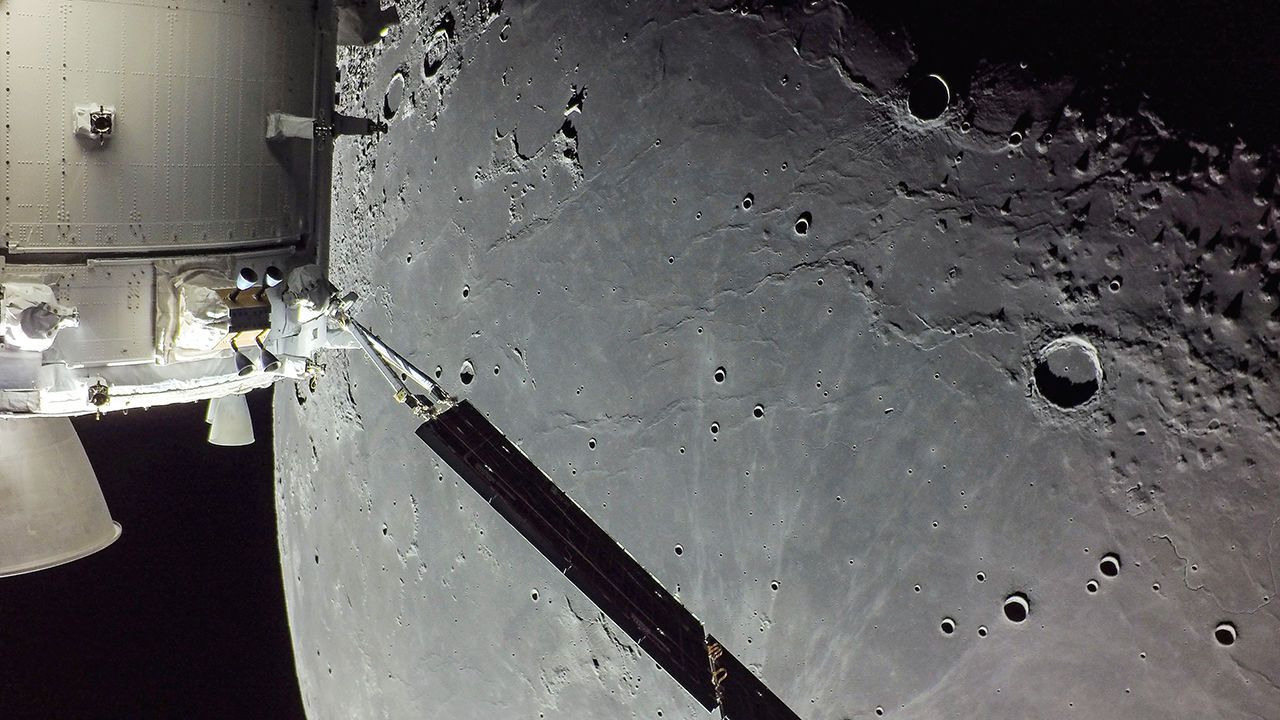 A portion of the Moon looms large just beyond the Orion spacecraft.