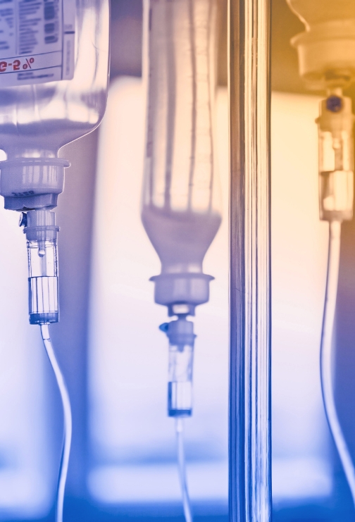 A blue and orange toned image displaying IV bags hanging on an IV pole.