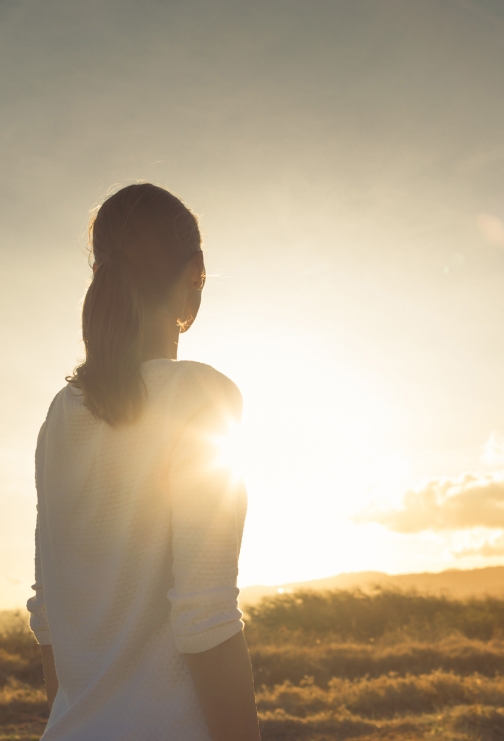 A woman looking into the sunset.