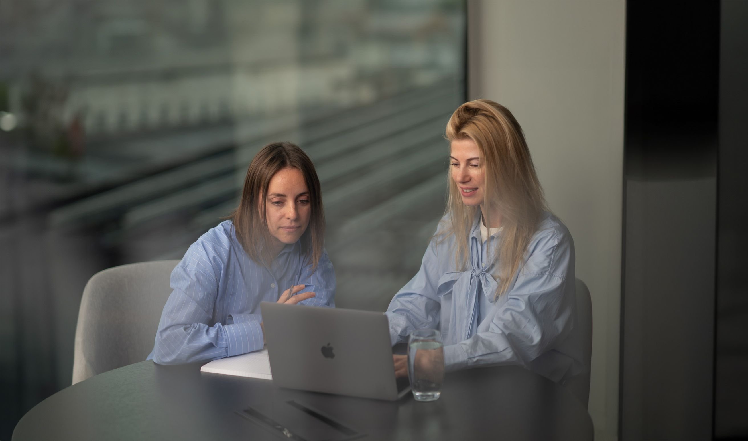 Two woman seated in front of notebook