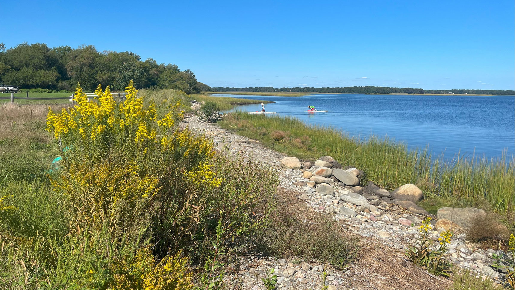 View of the project site with a path, grasses and water in view