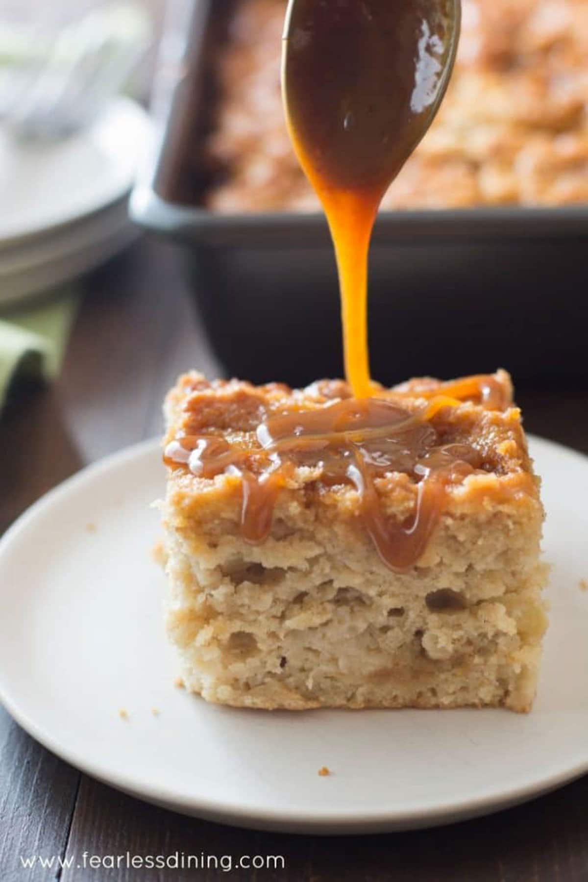 A slice of caramel apple cake with caramel being drizzled over the top.