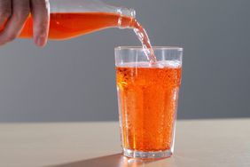 Bottle of orange soda pouring into glass