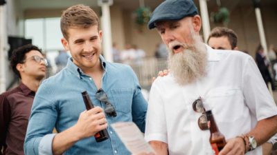 Two men at the races looking at ticket after having placed a bet