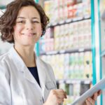 Female pharmacist smiles with a digital tablet.