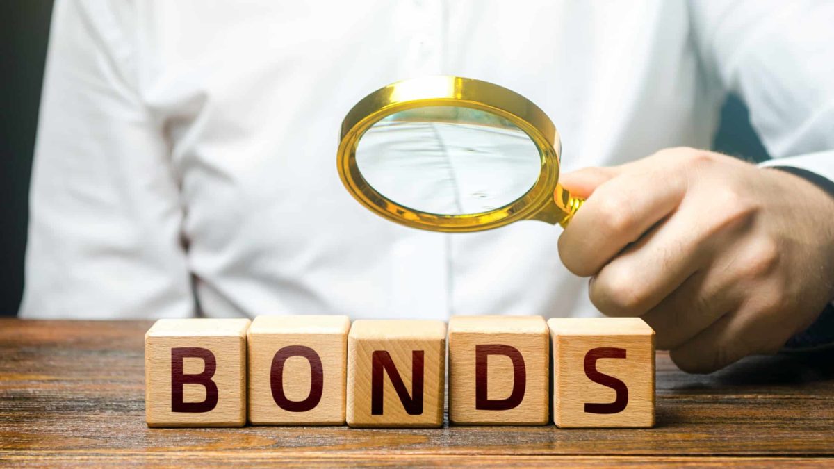 A magnifying glass on wooden blocks spelling out bonds.