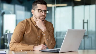 A man looking at his laptop and thinking.