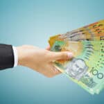 Hand holding Australian dollar (AUD) bills, symbolising ex dividend day. Passive income.