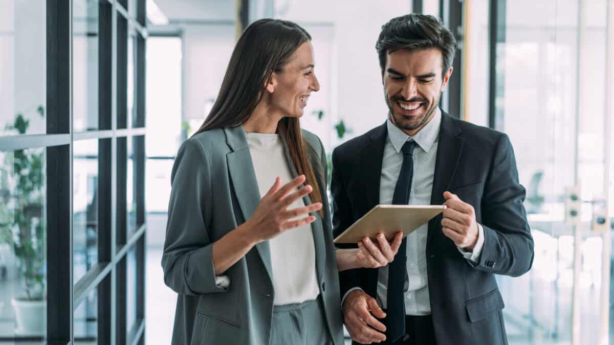 Two smiling work colleagues discuss an investment or business plan at their office.