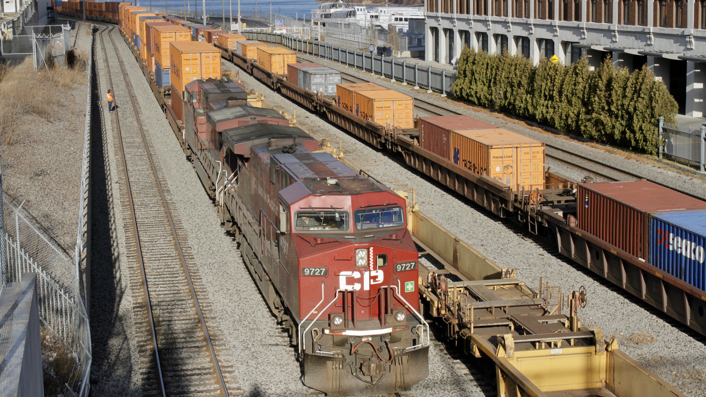 A Canadian Pacific train on train tracks with the port of montreal in the background.