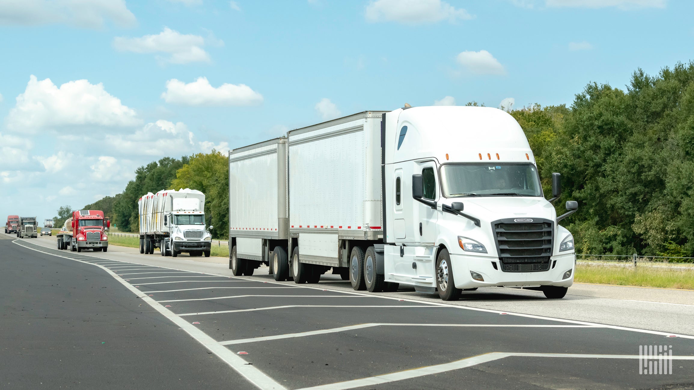 A white tractor with LTL trailers on the highway