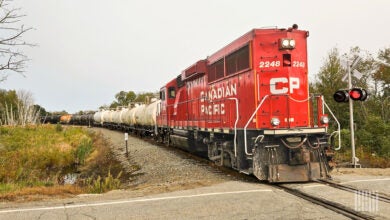 Image shows diesel locomotive and tank cars at grade crossing.