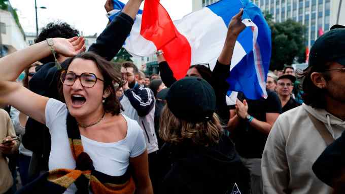People wave French flags as they react to projected results after the second round of the legislative elections, Sunday