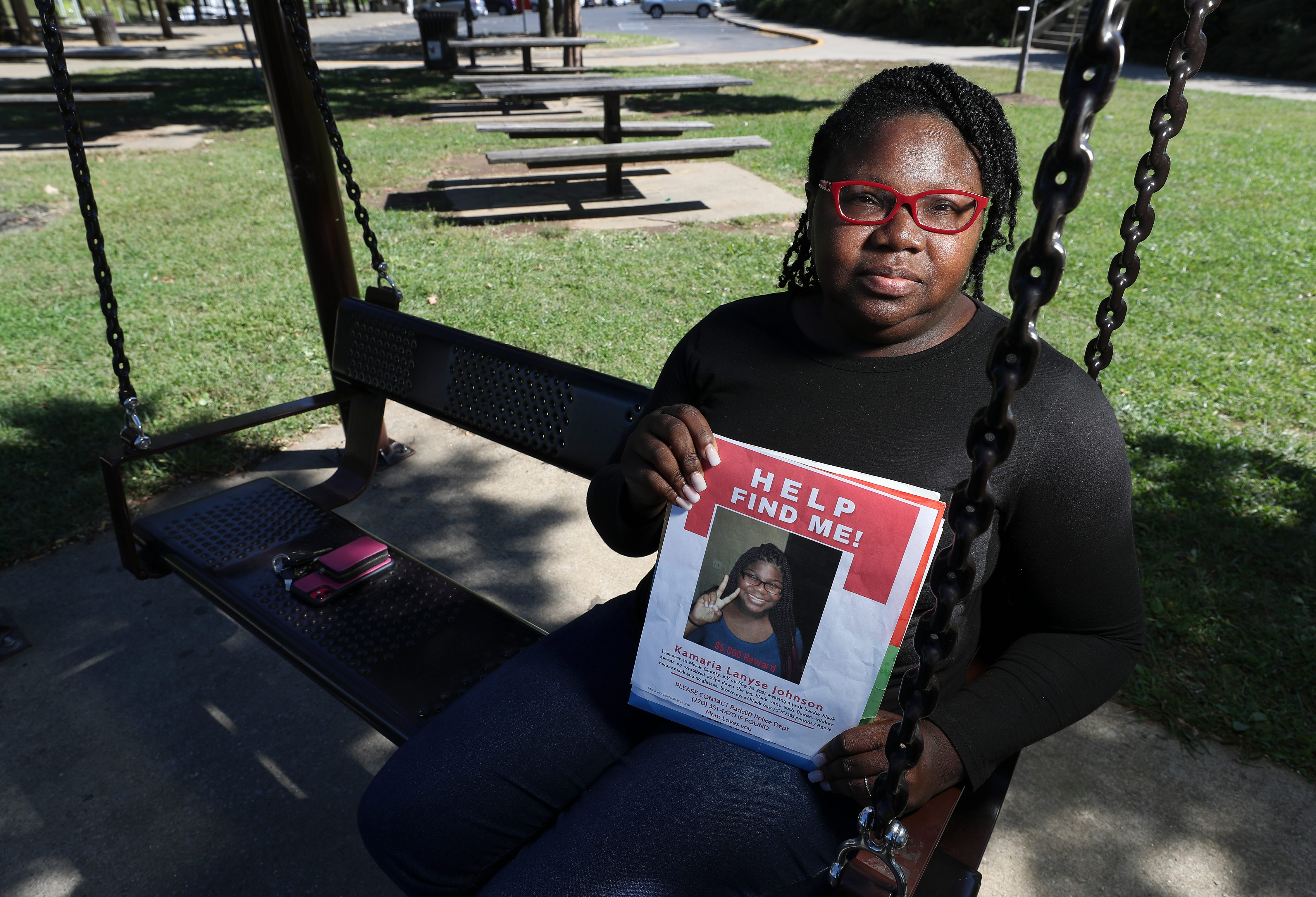 Consuela Jobe sits n a swing at the Big Four Lawn in Louisville, Kentucky, on Sept. 27, holding a photo of her daughter, Kamaria Johnson, who is missing.