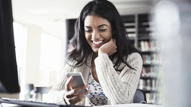 Female student using smartphone in college library