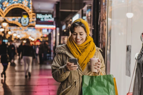 Happy woman in holiday shooping holding mobile phone