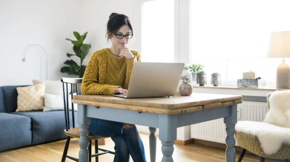 Woman sitting at table, using laptop