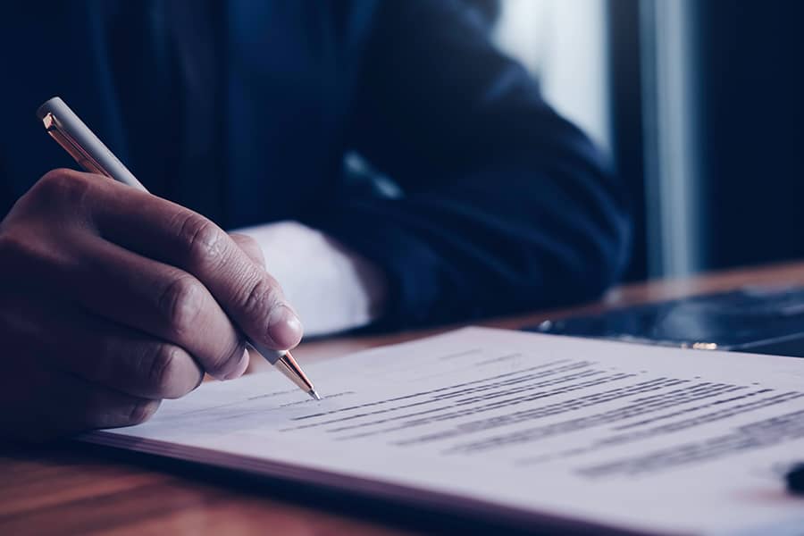 Close up of business person hand putting signing a contract.