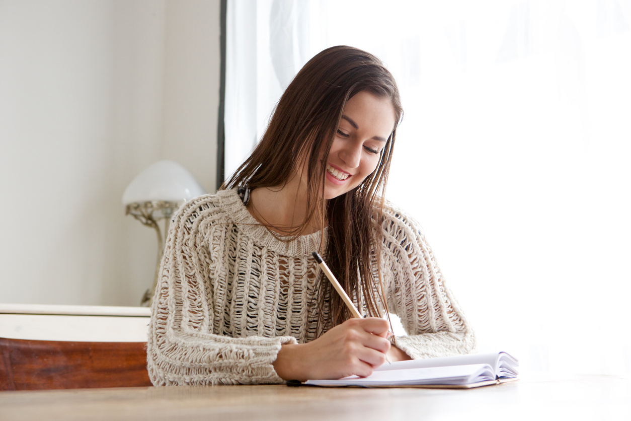 Portrait of female student sitting at desk and writing in books