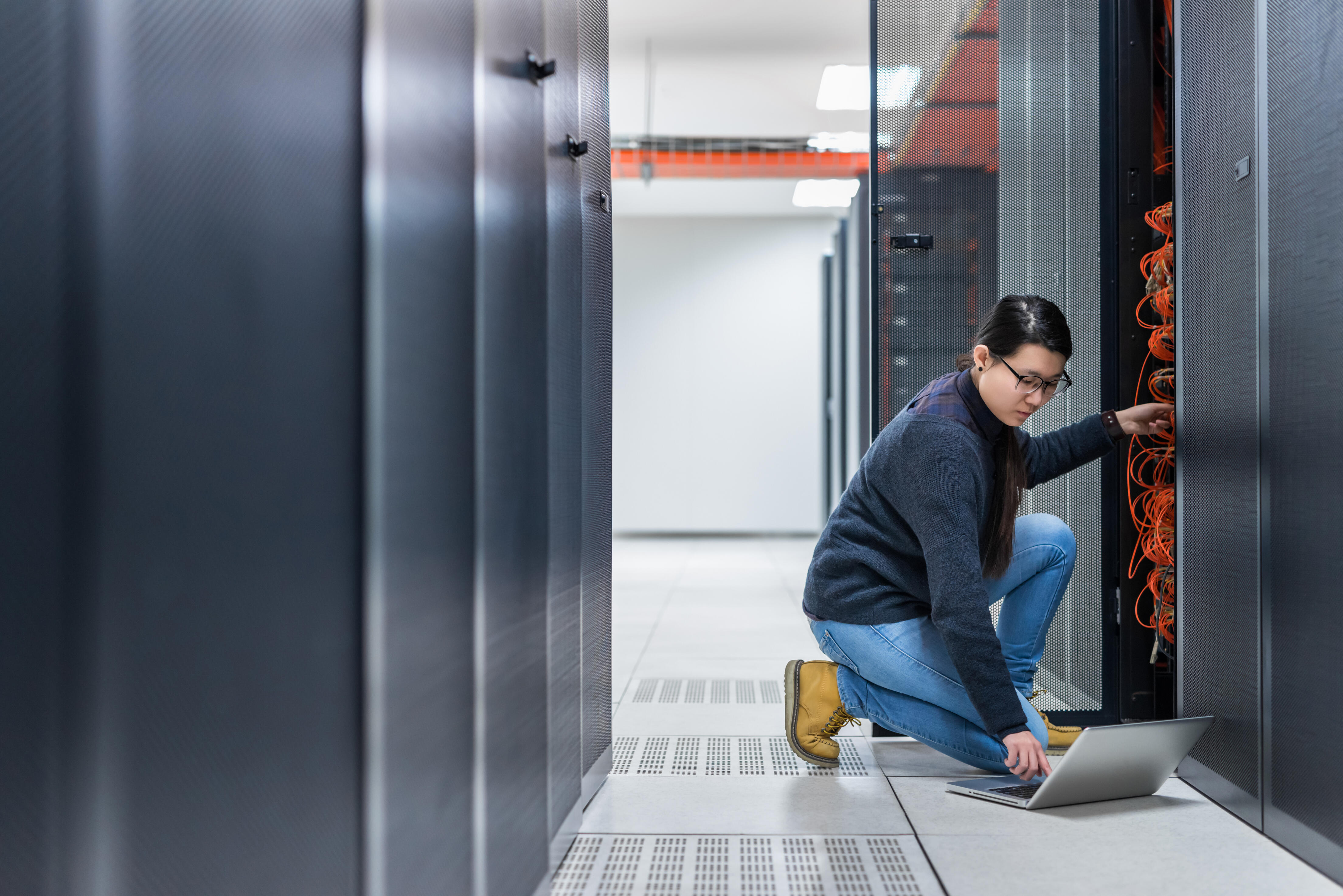 An individual working on a laptop in a data center